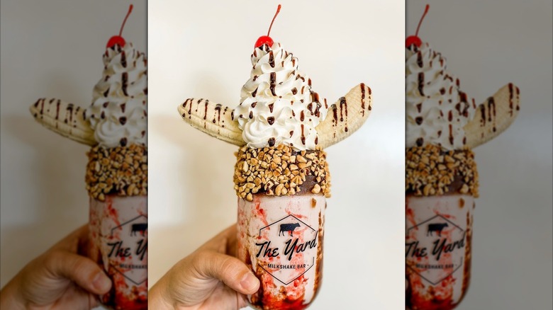 A classic banana split milkshake held in front of a white wall