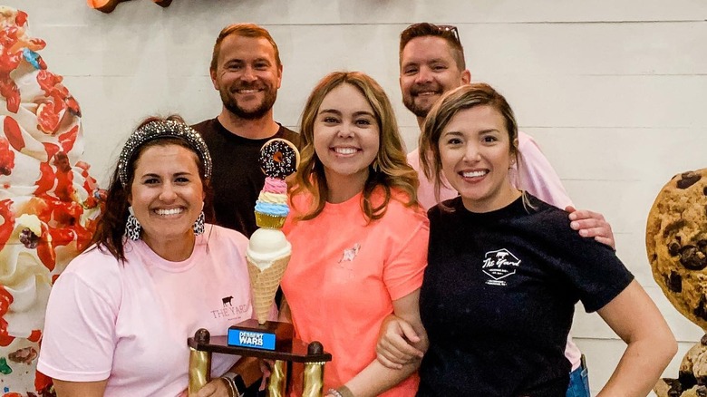 Logan and Chelsea Green outside The Yard with three employees holding a trophy