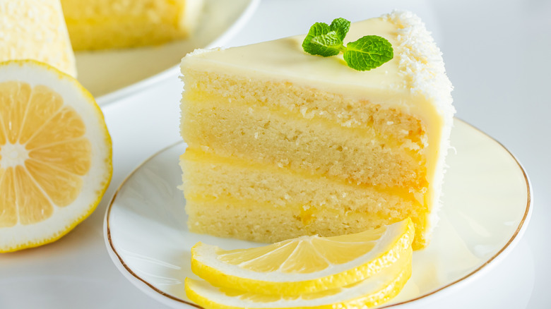 slice of lemon layer cake on white plate with lemon slices