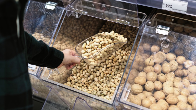 A customer scoops a spoonful of pistachios from a bulk bin