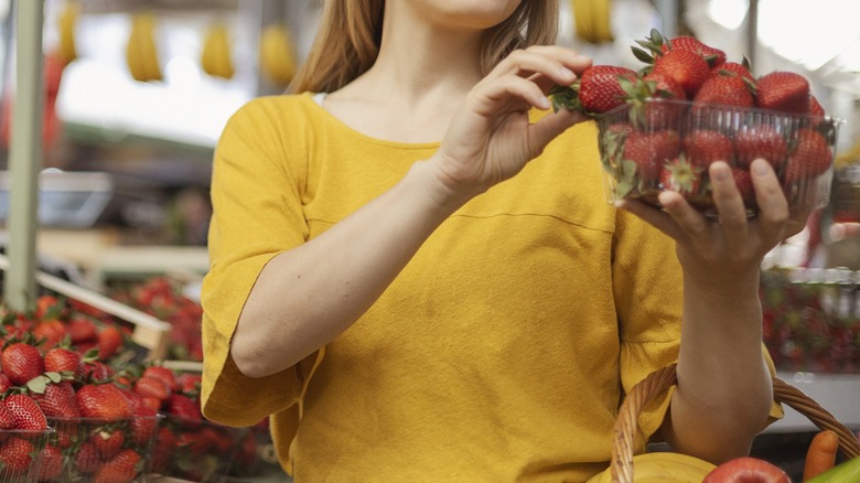 Woman inspecting strawberries at grocery store