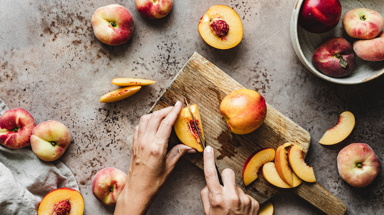 Hands slicing peaches 