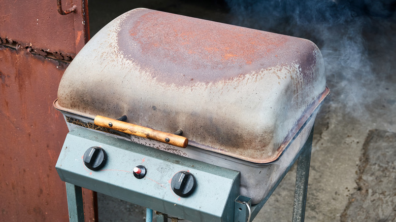 A dirty, rusted out grill lid