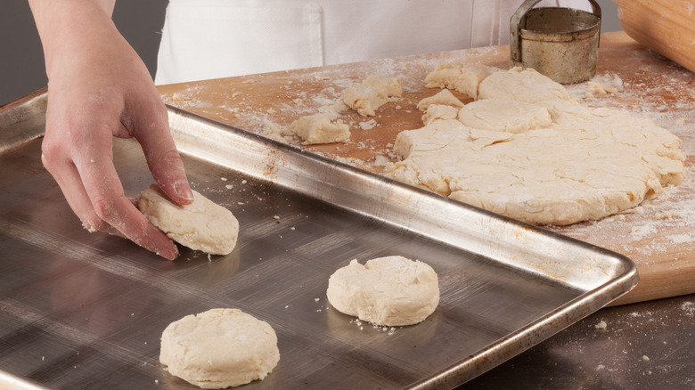 Placing round uncooked biscuits on sheet tray