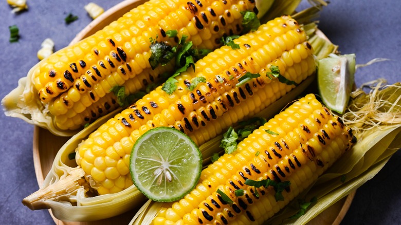 Grilled corn with lime garnish served on husks