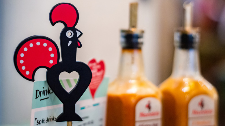 An interior shot of a Nando's, with a Nando's chicken mascot menu holder and hot sauce in view