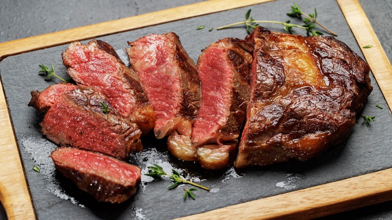 Cooked sliced ribeye steak on cutting board