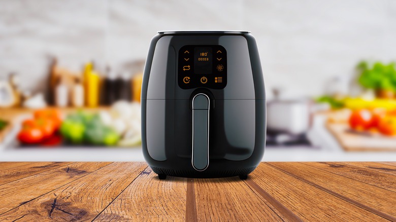 A black air fryer sitting on a wooden counter top