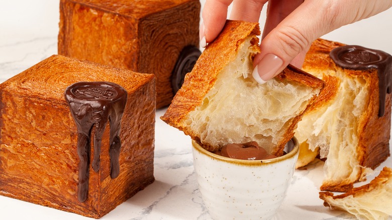Dipping cube croissant into Nutella