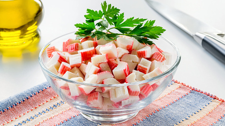 sliced surimi imitation crab sticks in a bowl with some fresh parsley garnish