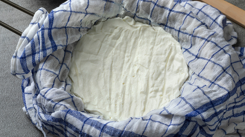 Plain yogurt is strained through a cloth to drain the whey