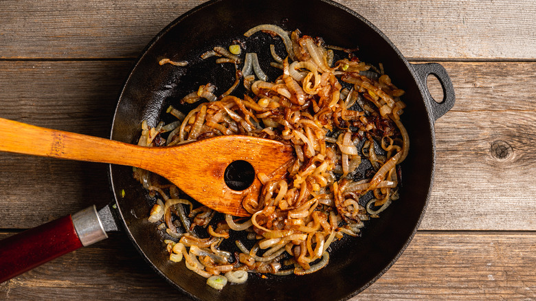 Wooden utensil stirring caramelized onions