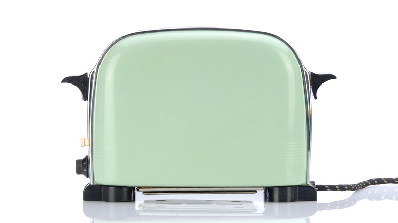 Teal toaster on a white counter with white background