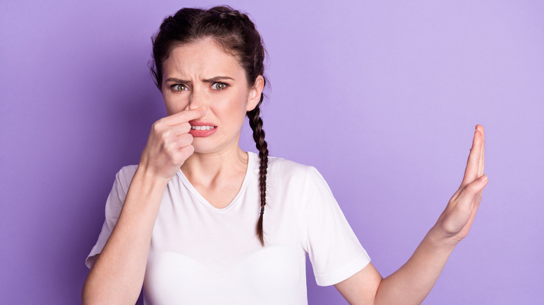 woman pinching nose because of bad smell