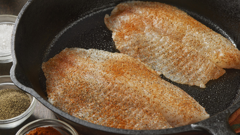 Spice-coated tilapia filets in a cast iron pan