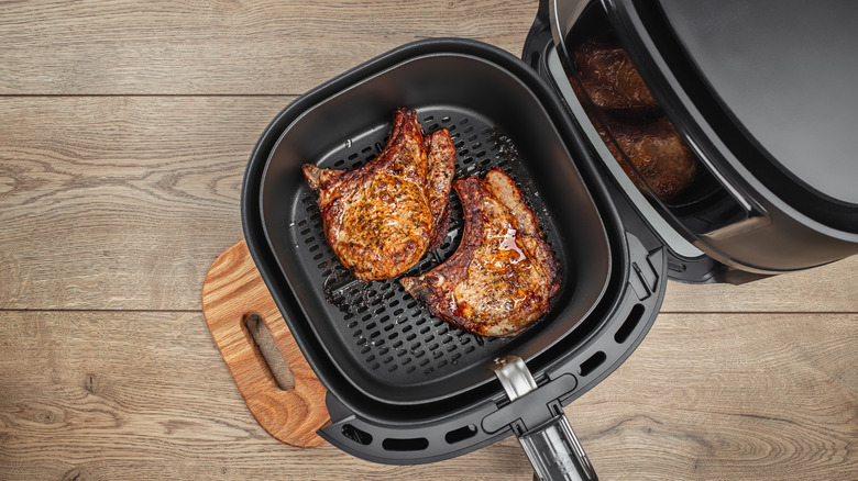 Two steaks in an air fryer basket can be viewed from overhead