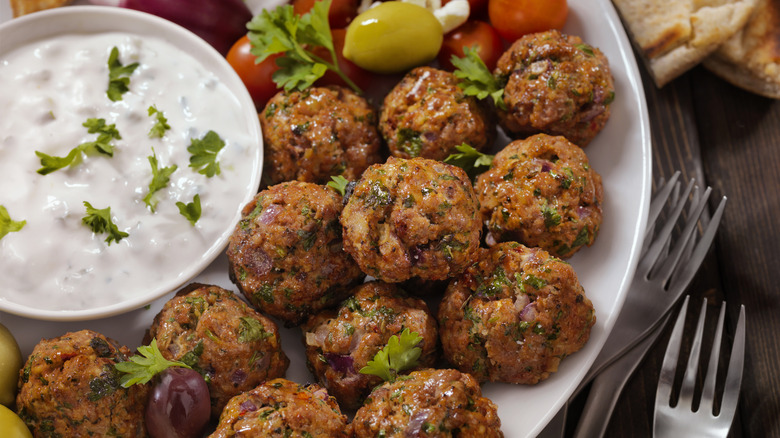 A platter of lamb meatballs sits alongside a bowl of tzatziki dip