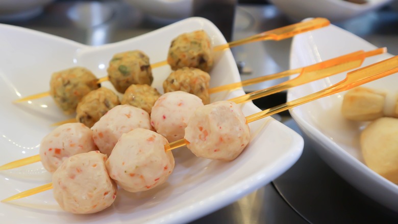 Meatballs made with shrimp and crab are stacked on orange colored skewers