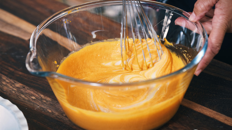 Whisking pumpkin pie filling in glass bowl