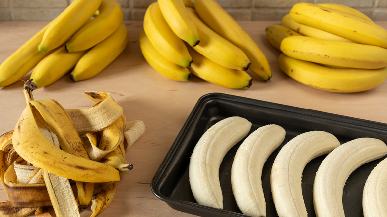 banana bunches next to tray of peeled bananas