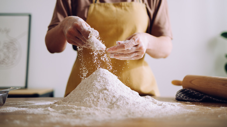 person handling flour on wooden counter