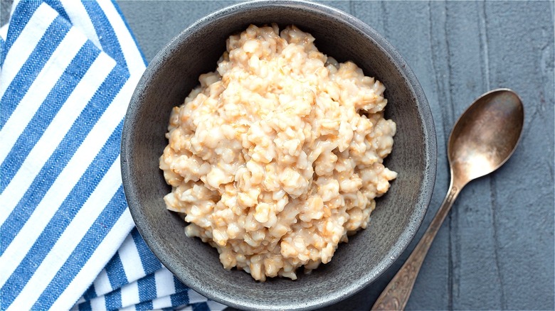 Cooked oatmeal in bowl with spoon