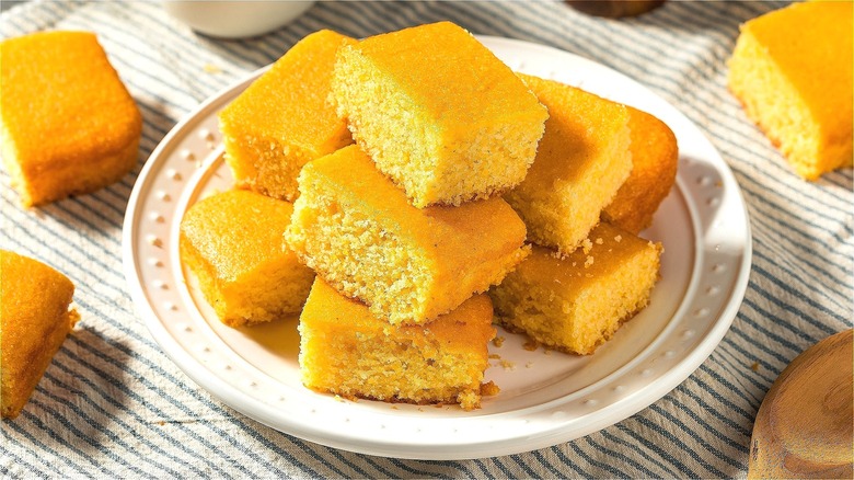 Square pieces of cornbread stacked on white plate