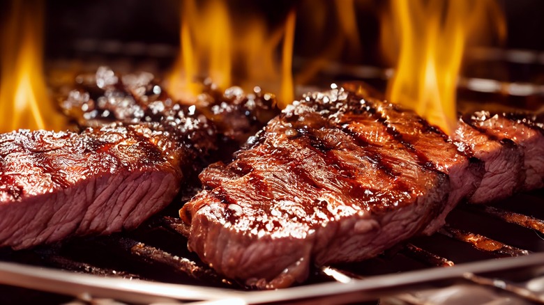 Steak getting grilled over flames