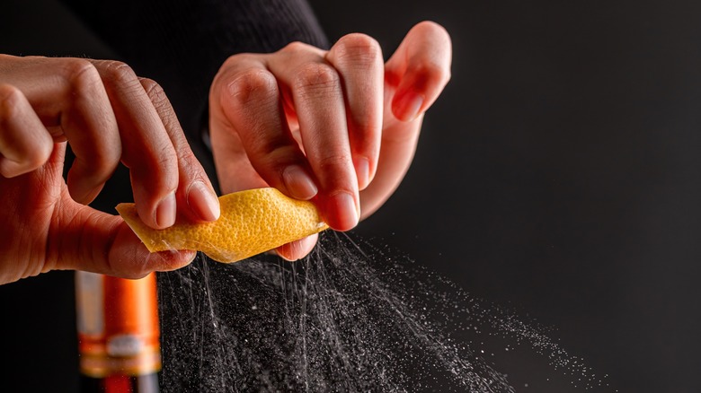 Hands expressing oil from lemon peel