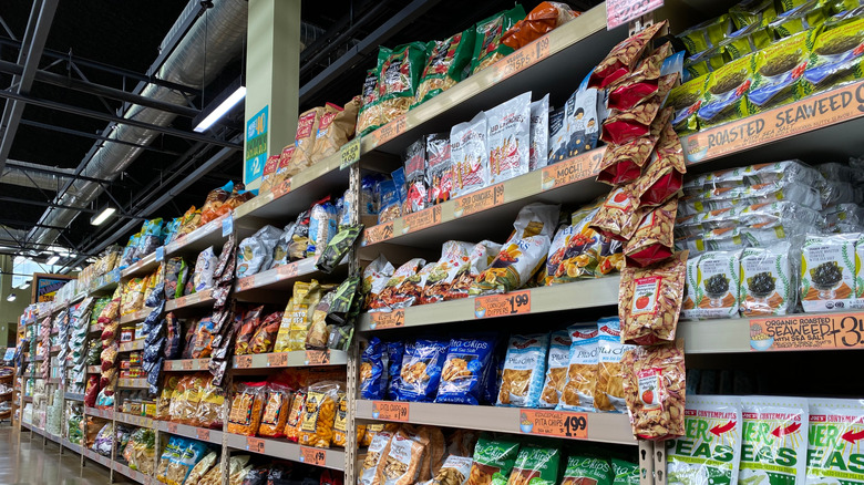 A Trader Joe's snack aisle is filled with Trader Joe's branded chips, granola, and seaweed snacks