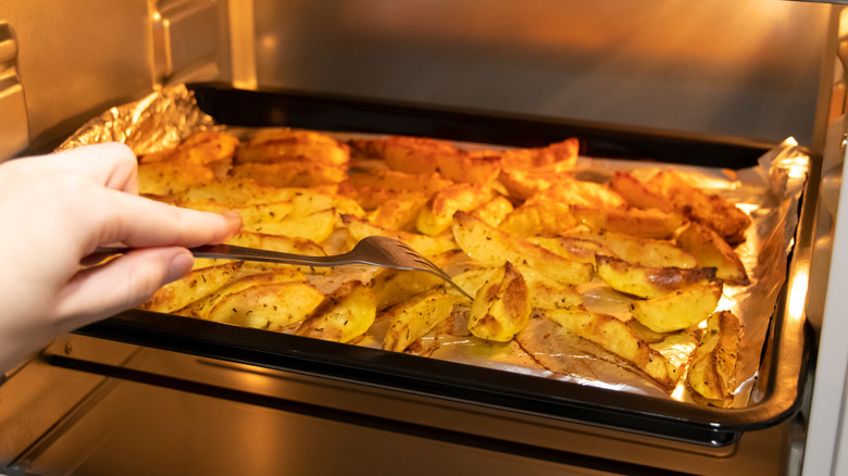 checking potatoes in oven