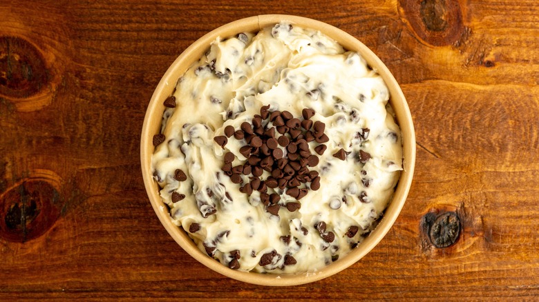 White cannoli dip with brown chocolate chips in a cream-colored bowl on a knotted wood surface