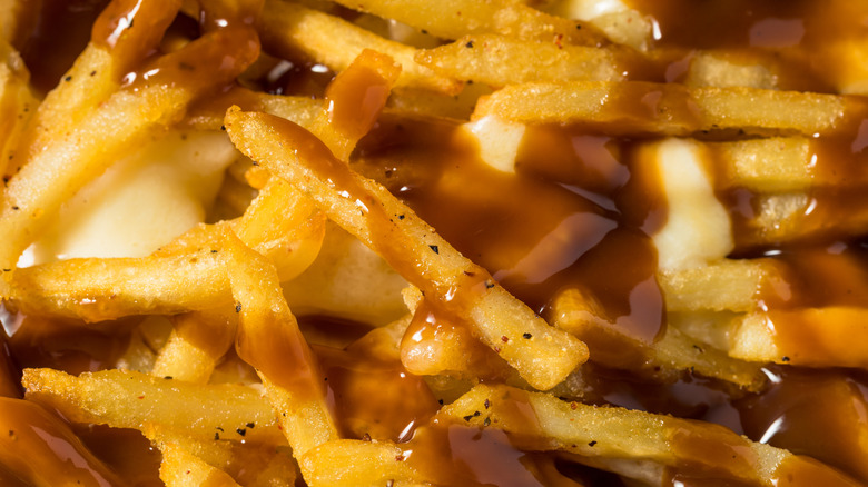 A slew of french fries is covered with brown gravy, pepper, and melty cheese curds