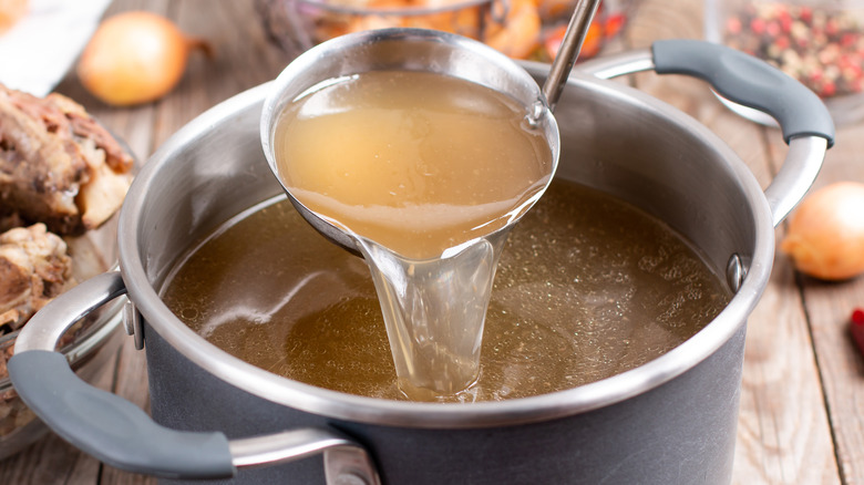 A pot of stock with a ladle 