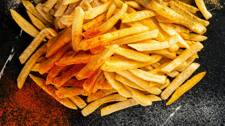 fries on a black plate covered with chilli seasoning