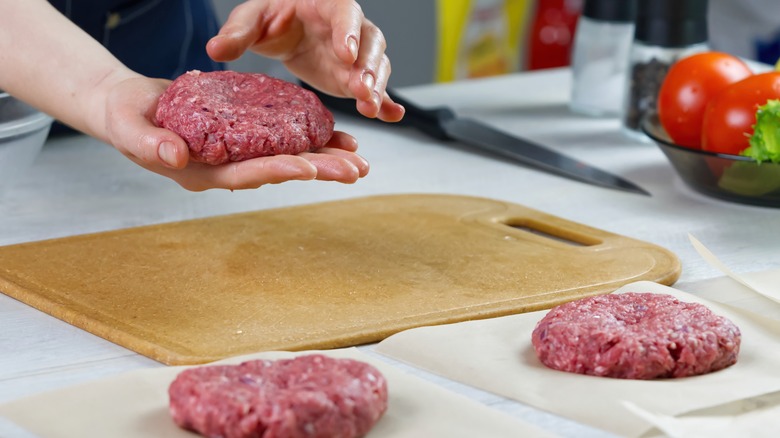 woman forming burgers with raw meat