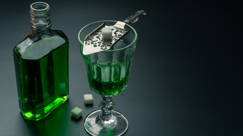 A bottle of absinthe with a glass