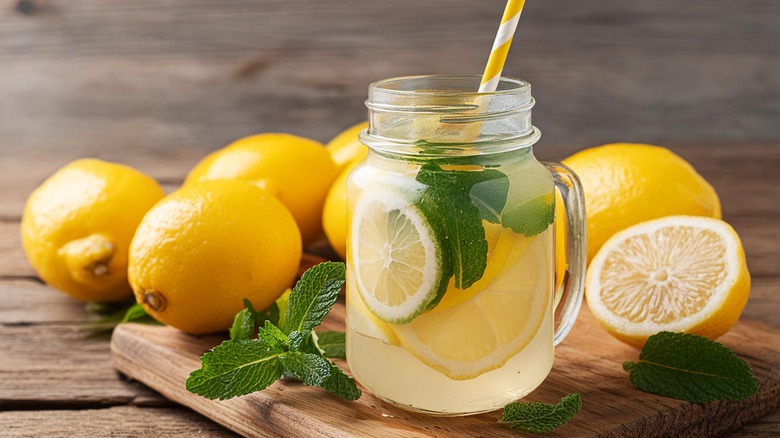 mason jar of lemonade with whole lemons and mint leaves