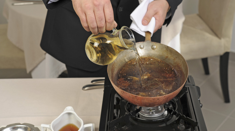 Hand pouring liquid into frying pan