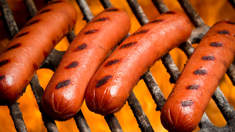 Closeup of four hot dogs cooking on an outdoor grill