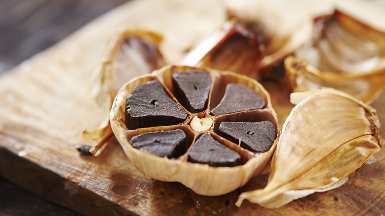 A bulb of black garlic that has been cut in half, revealing the deep, dark color of the cloves within