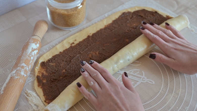 Person rolling up homemade cinnamon rolls