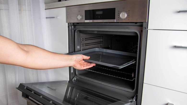 An arm placing a sheet pan into an oven