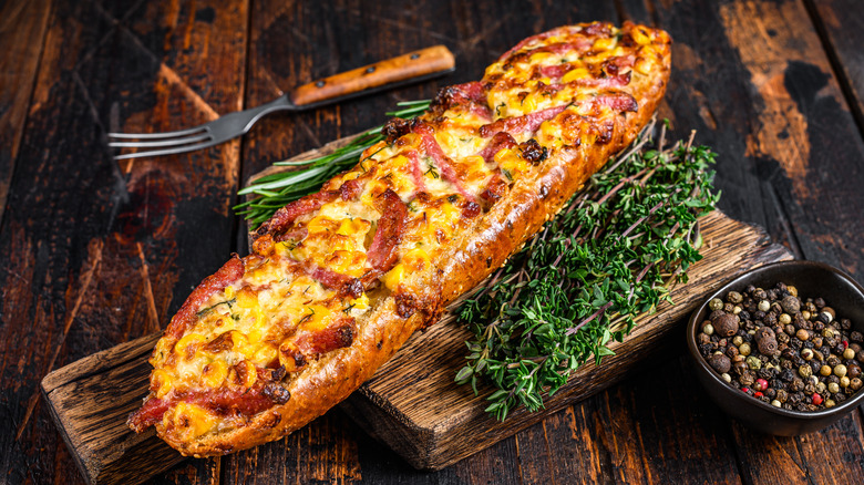 French bread topped with cheese and bacon on top of herbs