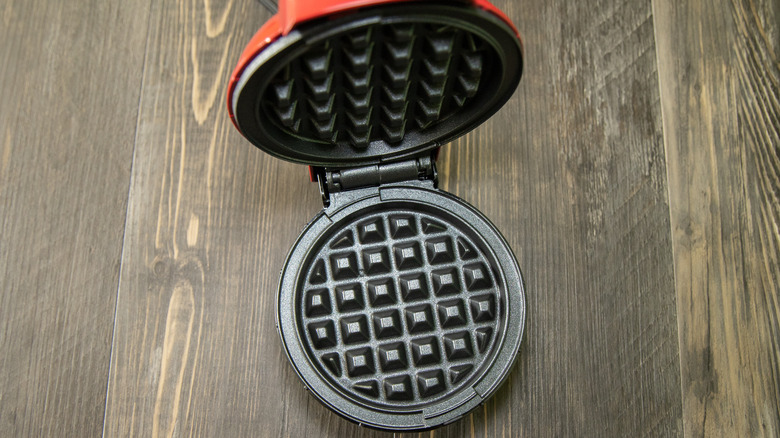Mini waffle maker with lid open on kitchen surface
