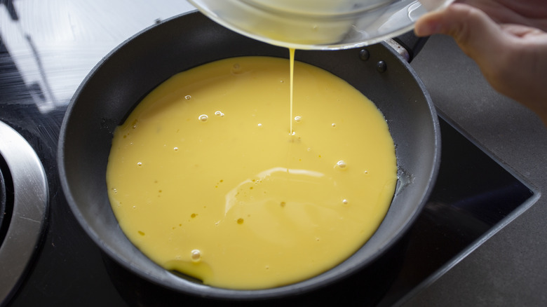 Uncooked scrambled eggs in a black pan