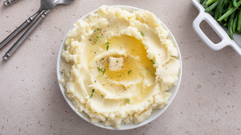 Fluffy mashed potatoes with melted butter in white serving bowl