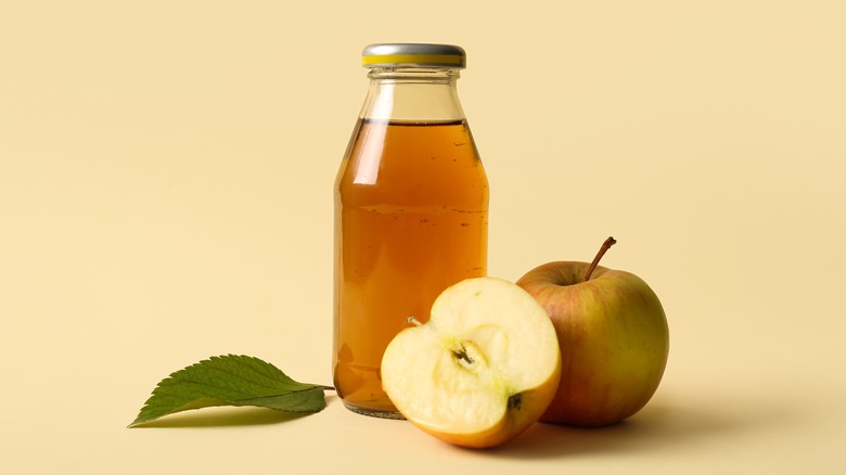 A bottle of apple juice with apples