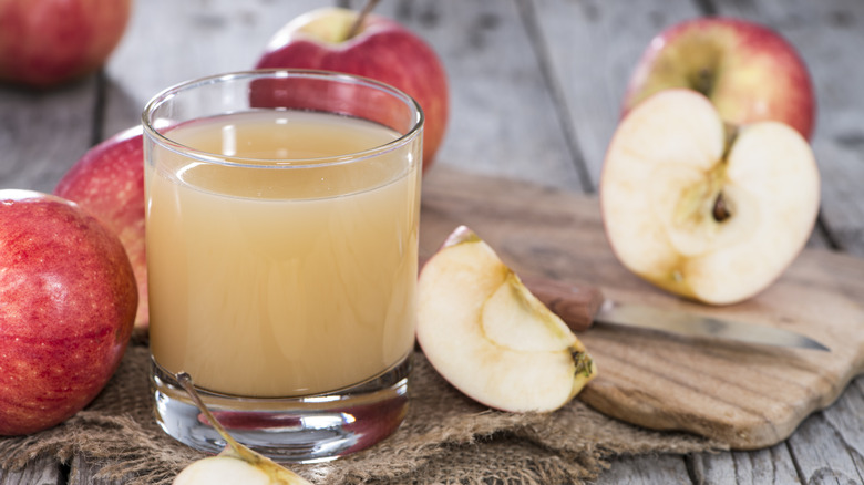 A glass of apple juice with apples