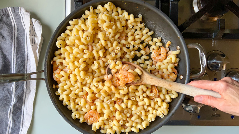 Pasta, shrimp and cannellini beans in skillet on stove